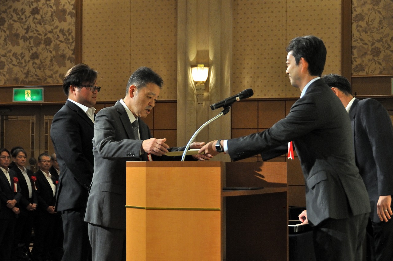 優良建設工事の表彰状を萩原代表取締た役(中央)、優秀技術者の表彰状を小川氏(左)が受け取った